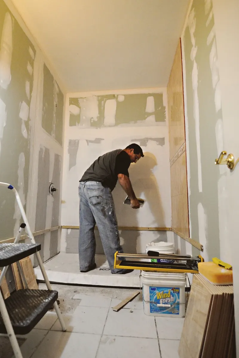 Artisan préparant les murs d'une salle de bain en rénovation