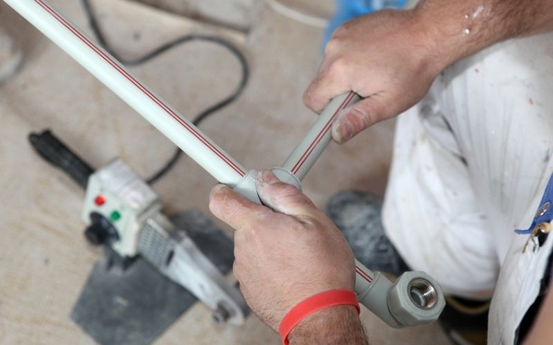 Plombier coupant un tube multicouche pour une réparation