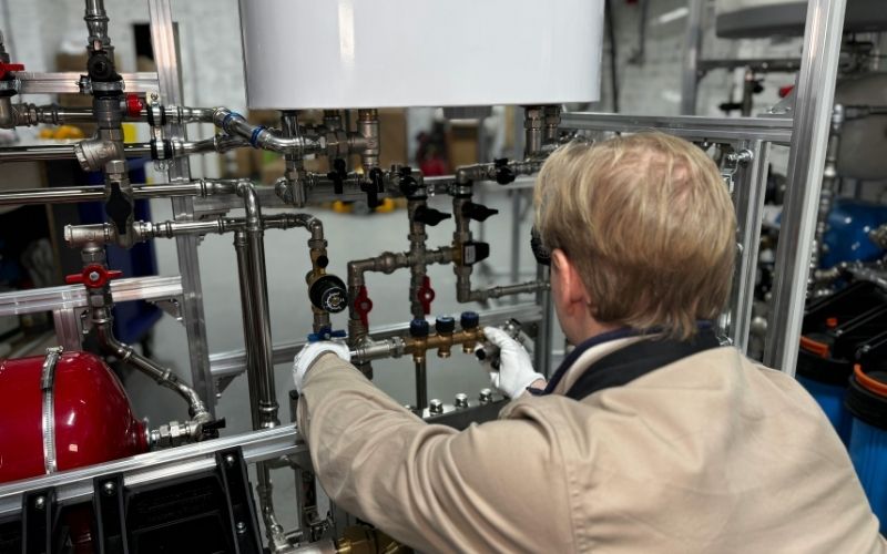 Plombier intervenant sur une installation de distribution d'eau en sous-sol