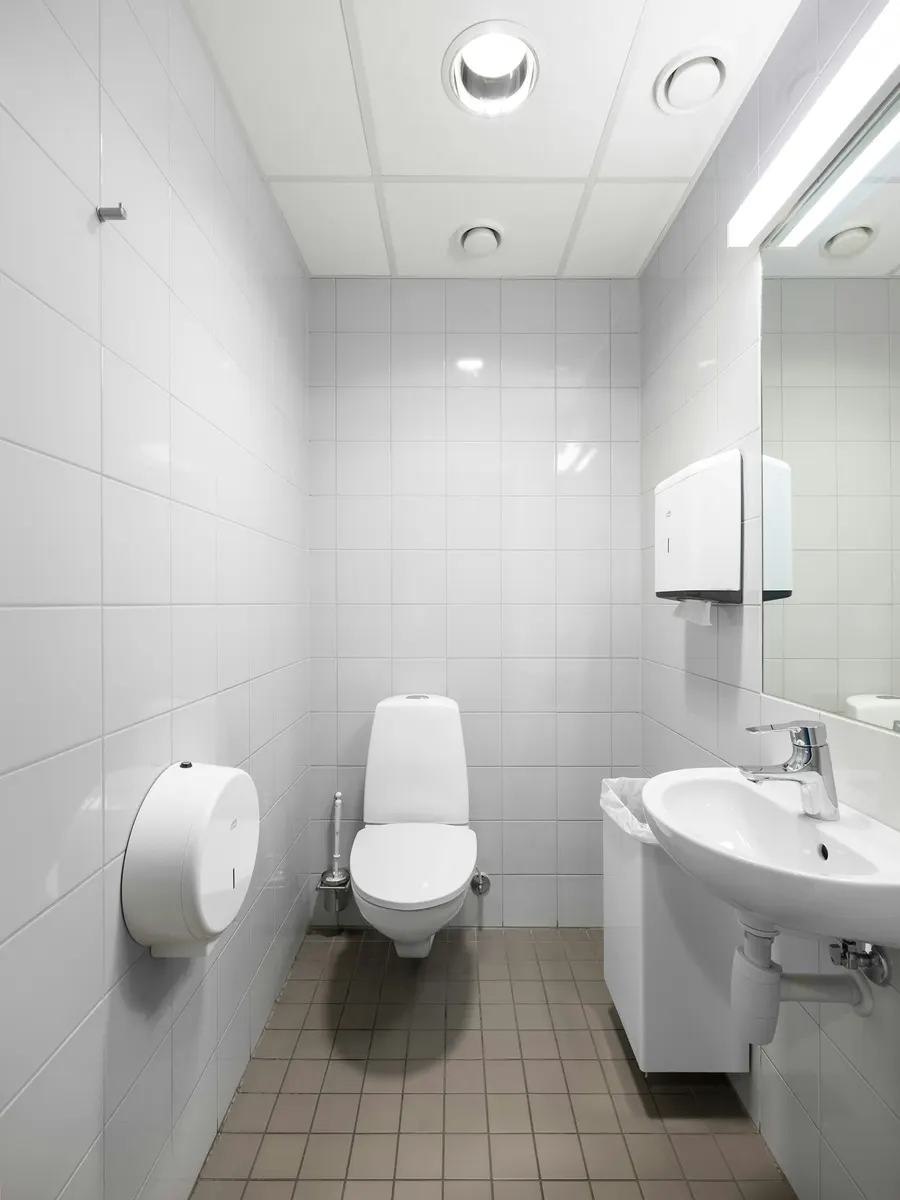 WC suspendu et lave-mains dans un espace sanitaire carrelé blanc
